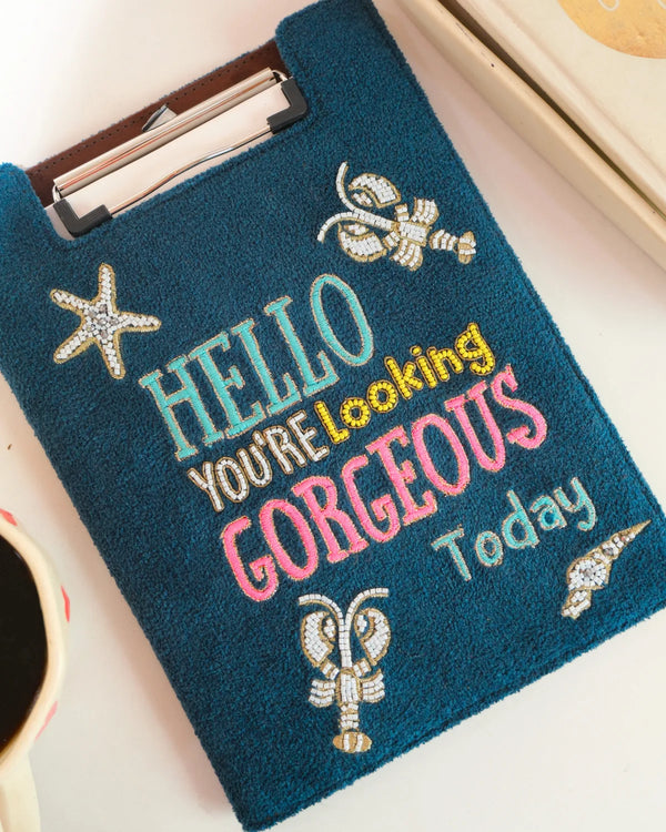 Teal pouch with decorative text and embellishments on a light background
