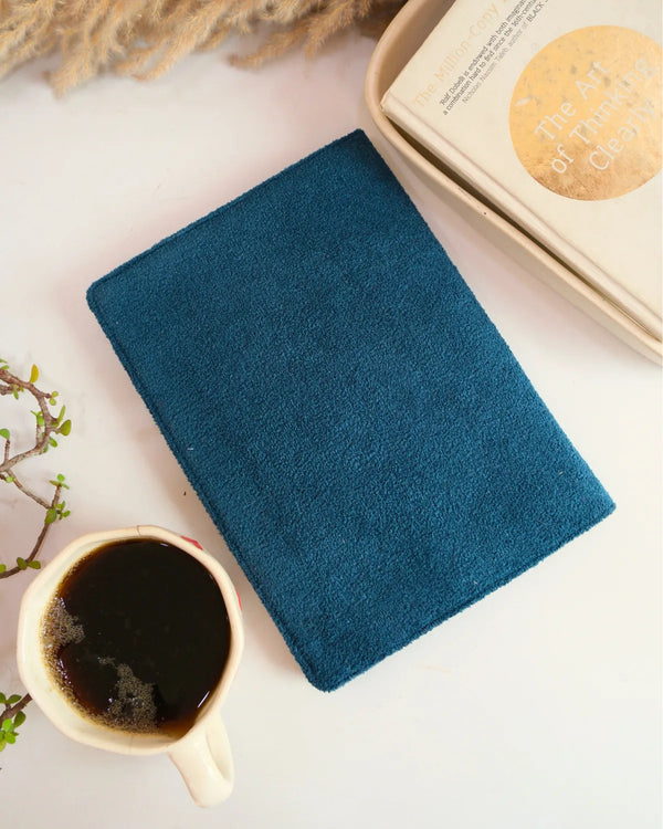 Teal notebook with a cup of coffee on a light surface