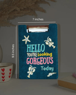 Blue clipboard with decorative text and measurements on a neutral background