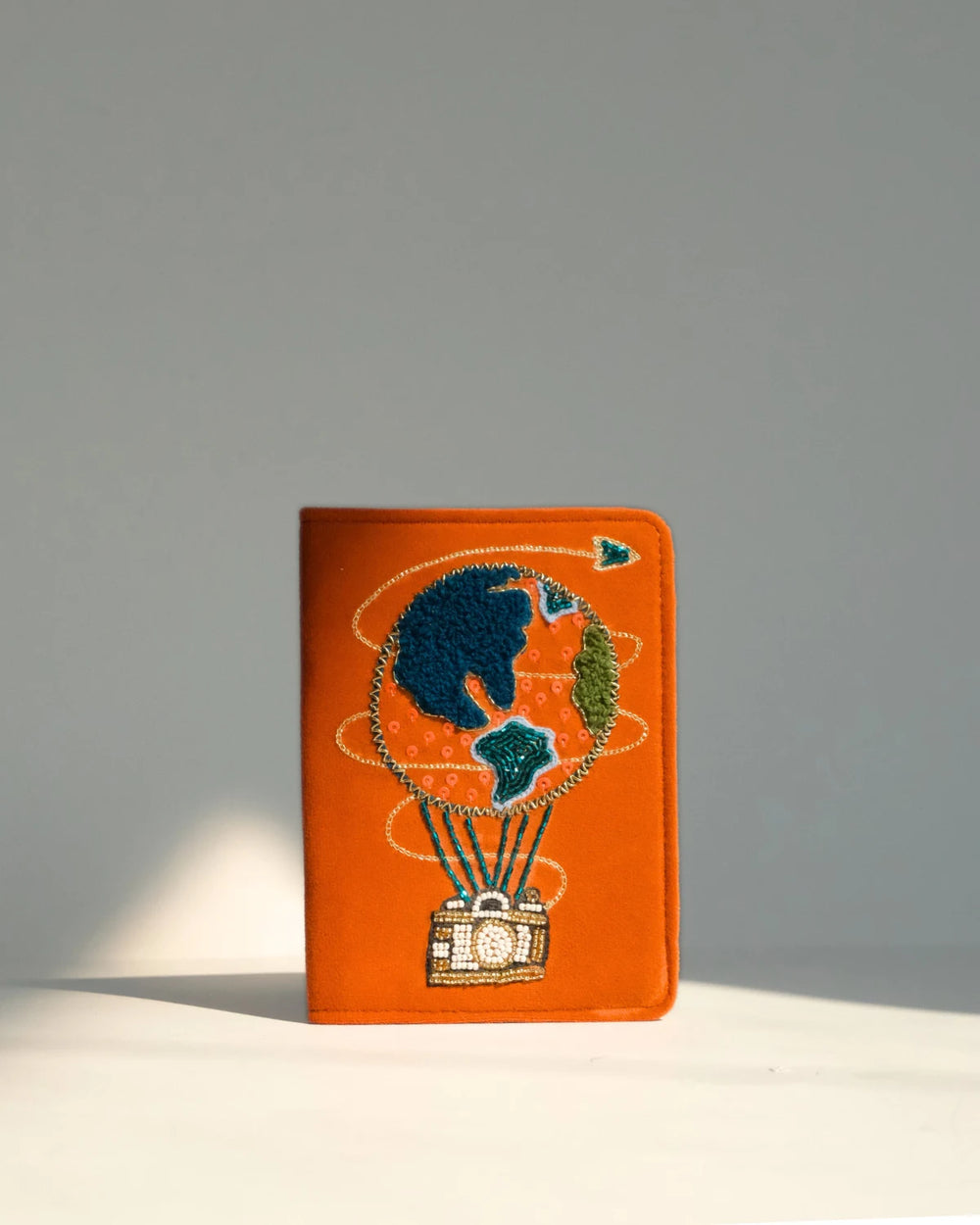 Orange passport holder with hot air balloon design on a gray background