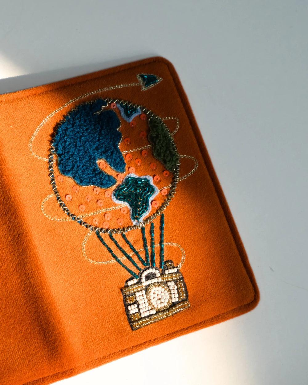 Orange passport holder with hot air balloon design on a gray background