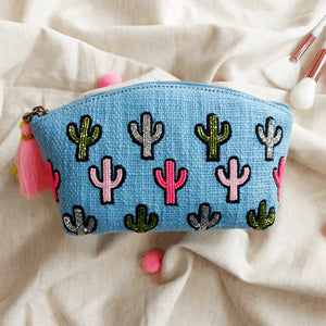Blue pouch with cactus patterns and tassels on a beige fabric background
