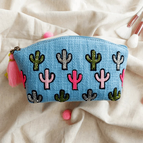 Blue pouch with cactus patterns and tassels on a beige fabric background