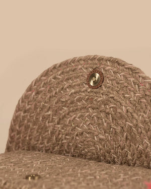 Close-up of a brown textured fabric cap with a button on a beige background