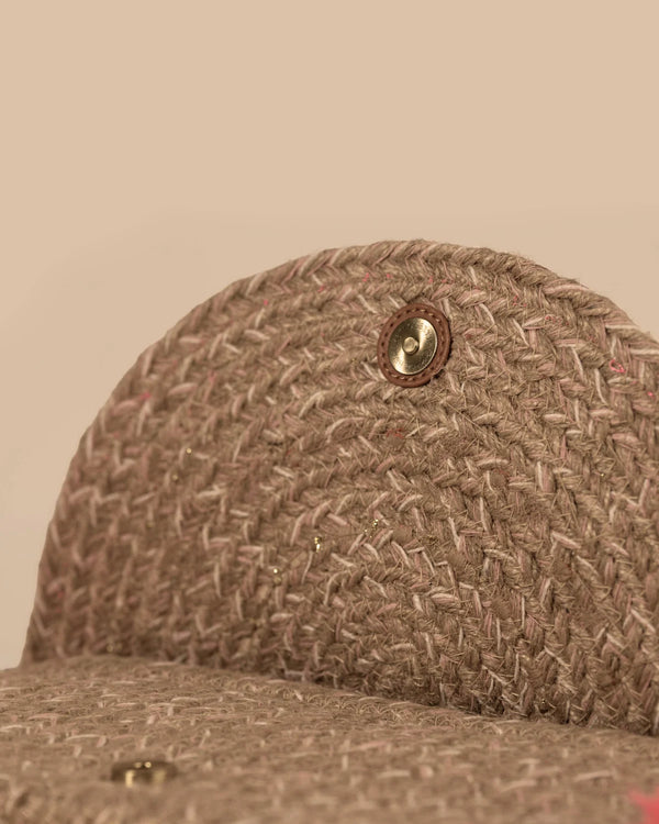 Close-up of a brown textured fabric cap with a button on a beige background