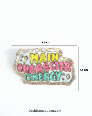 Colorful embroidered brooch with “Main Character Energy” text