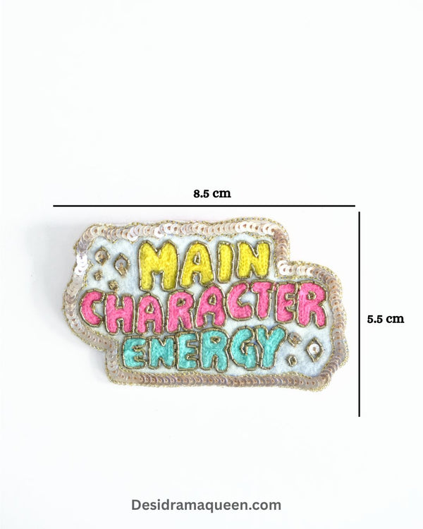 Colorful embroidered brooch with “Main Character Energy” text