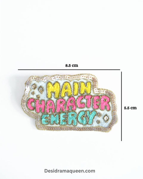 Colorful embroidered brooch with “Main Character Energy” text