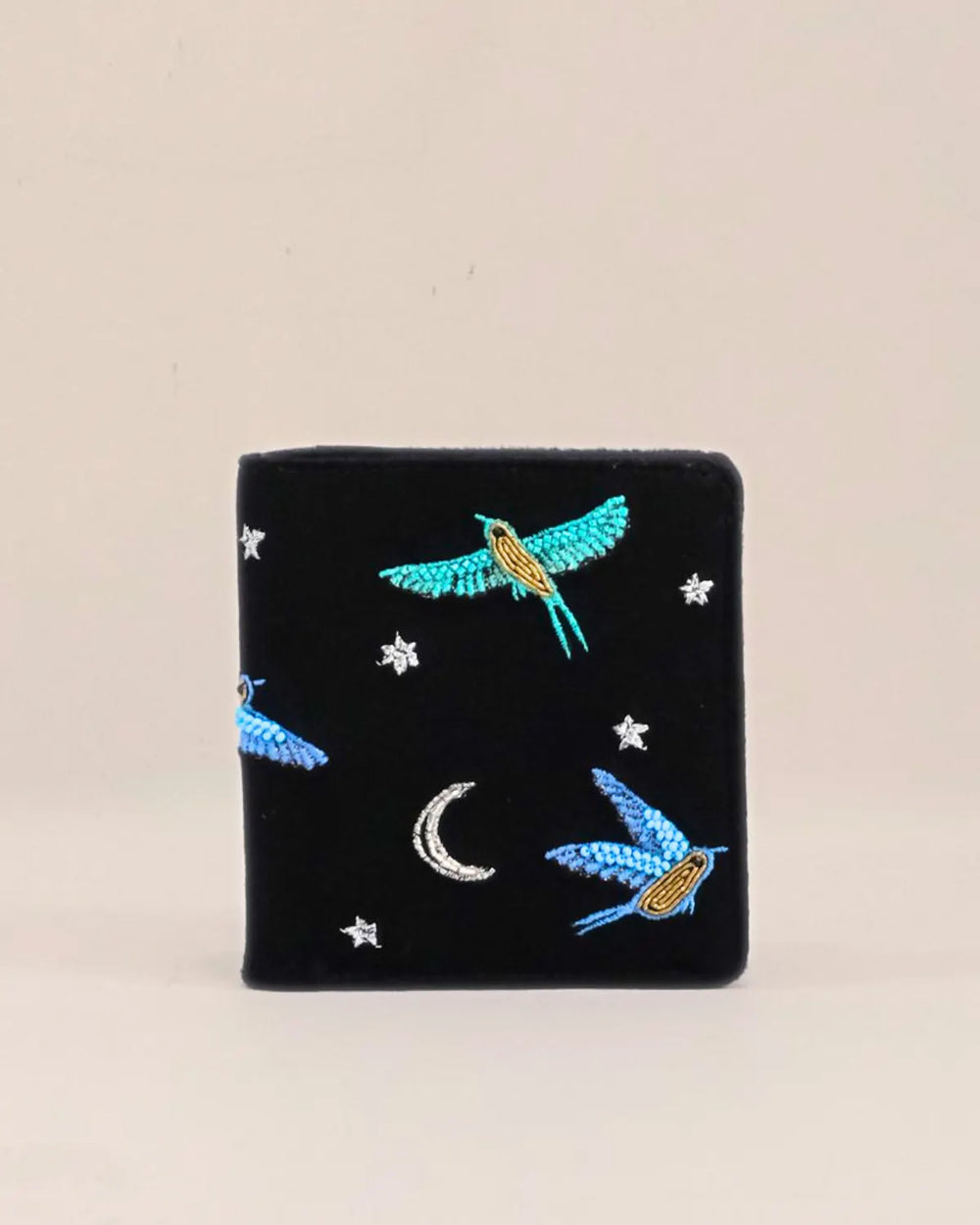 Black embroidered wallet with birds and stars on a beige background