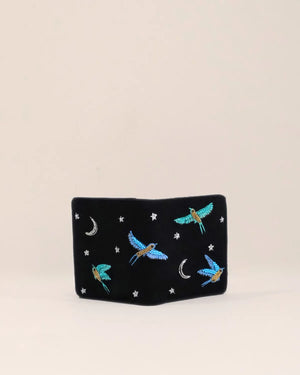 Black pouch with embroidered blue birds and stars on a beige background