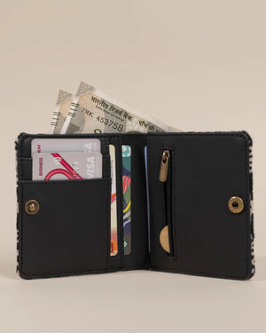 Black wallet with card slots and currency notes on a beige background