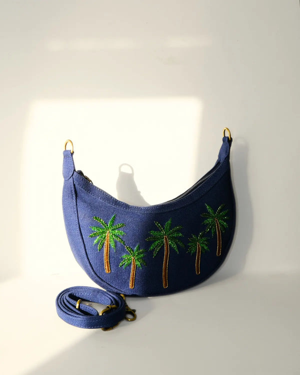 Blue handbag with palm tree embroidery on a white background