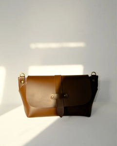 Brown leather bag with gold hardware on a white background