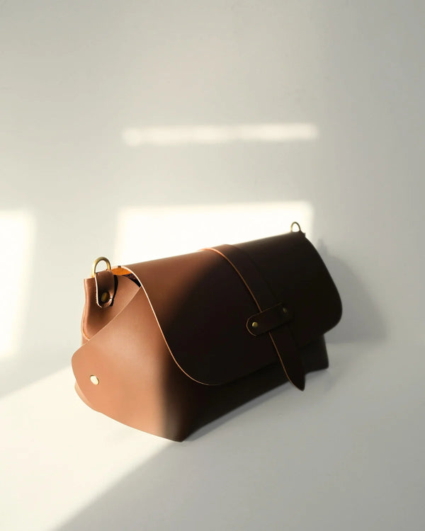 Brown leather handbag on a white surface with a light gray background