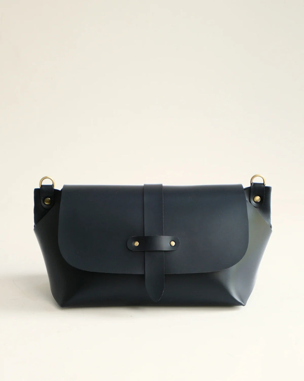 Navy blue leather handbag with gold accents on a light beige background