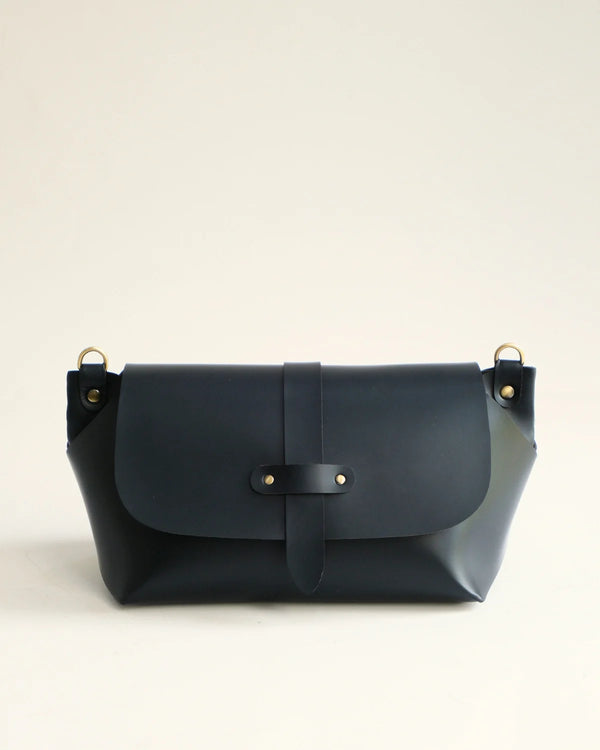 Navy blue leather handbag with gold accents on a light beige background