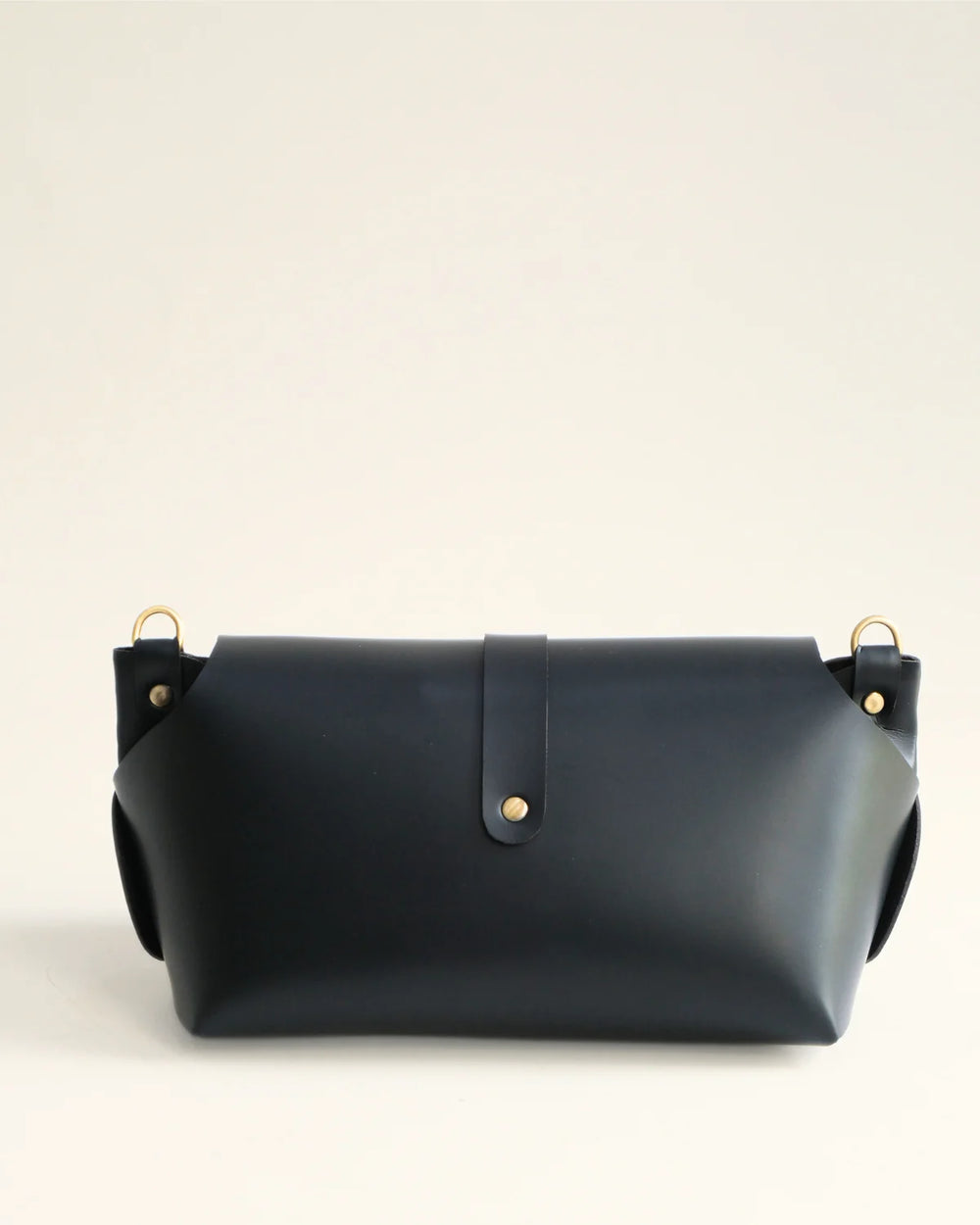 Navy blue leather handbag with gold accents on a light beige background
