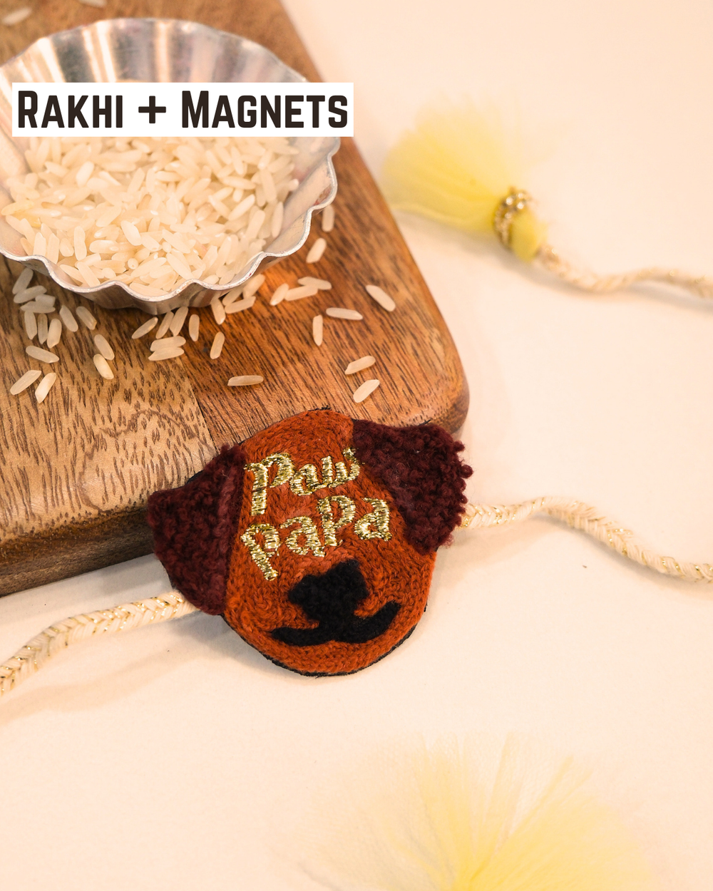 Paw Papa embroidered rakhi magnet placed beside a bowl of rice, styled for a festive Raksha Bandhan celebration.