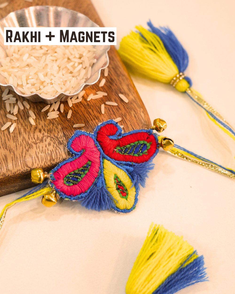 Titli-Kairi embroidered rakhi magnet placed beside a bowl of rice, beautifully styled for a festive Raksha Bandhan celebration.