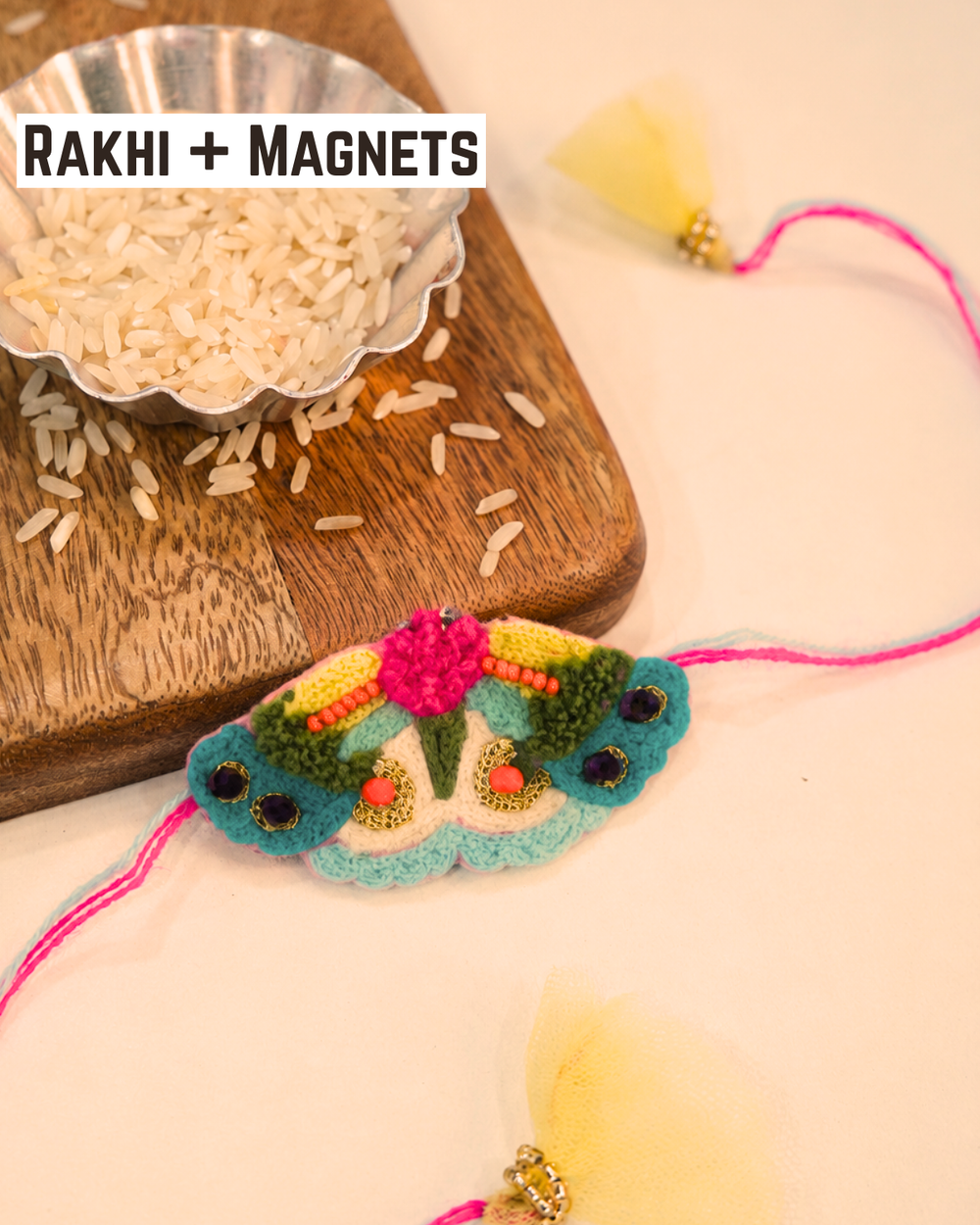 Butterfly embroidered rakhi magnet placed beside a bowl of rice, beautifully styled for a festive Raksha Bandhan celebration.
