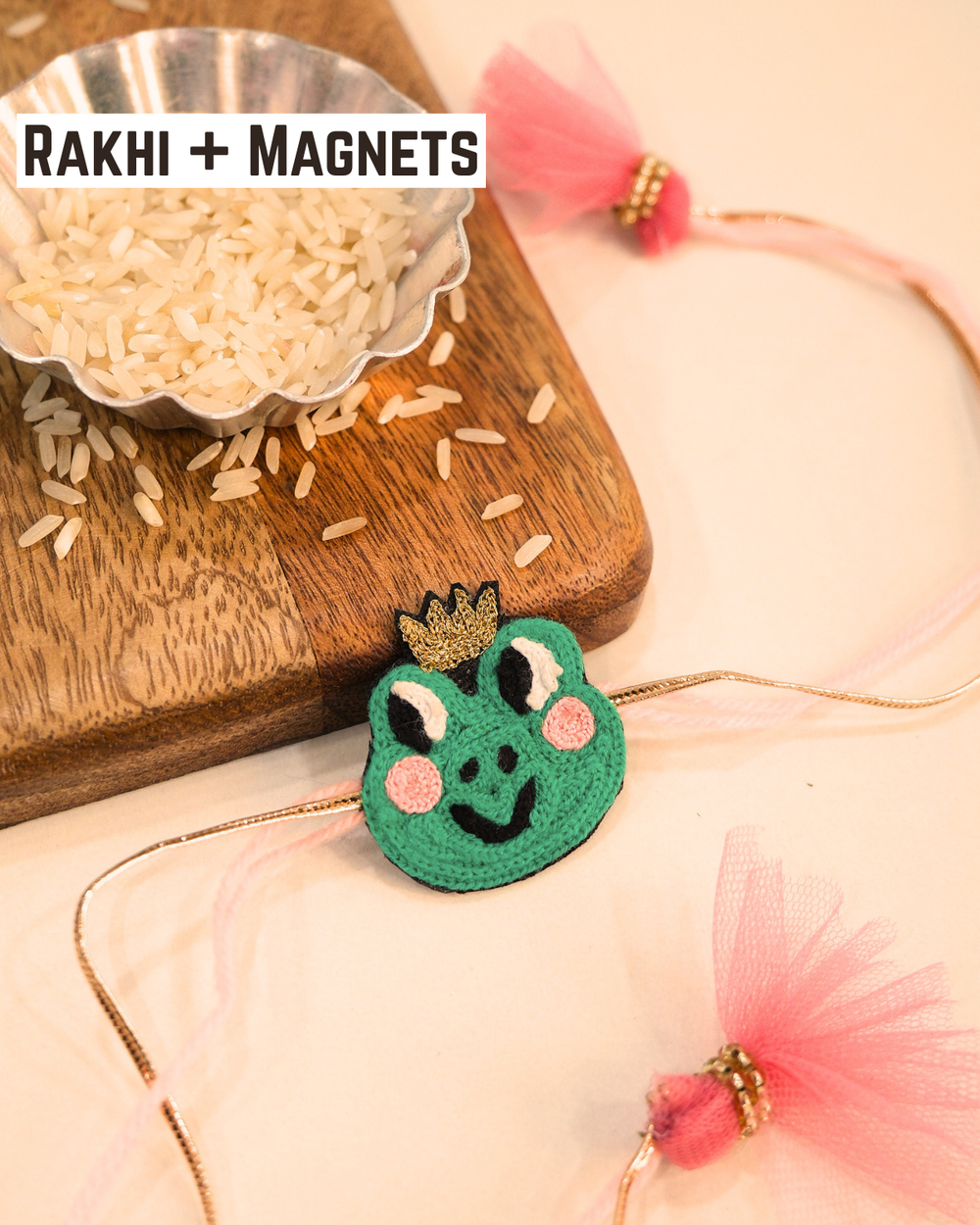 Cute Frog Prince Rakhi magnet displayed with soft pink threads and tassels, adding a playful touch to Raksha Bandhan celebrations.