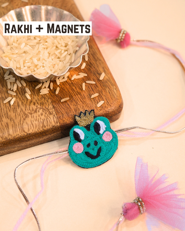 Cute Frog Prince Rakhi magnet displayed with soft pink threads and tassels, adding a playful touch to Raksha Bandhan celebrations.