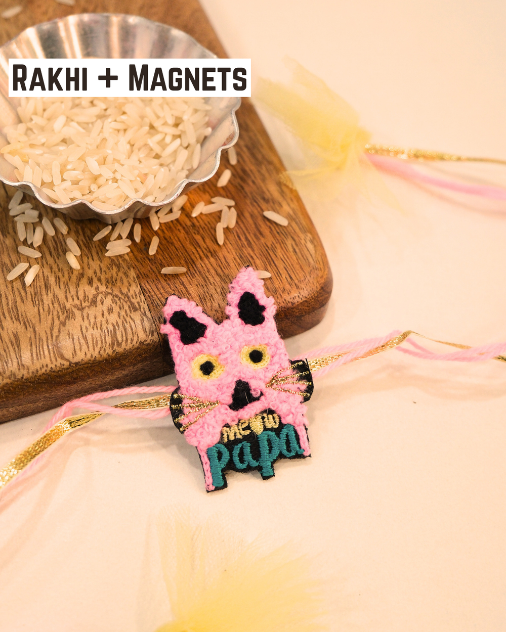 Meaw Papa embroidered rakhi magnet placed beside a bowl of rice, styled for a festive Raksha Bandhan celebration.