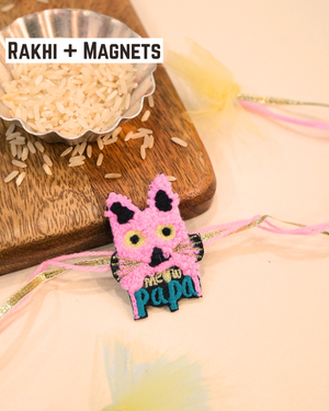 Meaw Papa embroidered rakhi magnet placed beside a bowl of rice, styled for a festive Raksha Bandhan celebration.