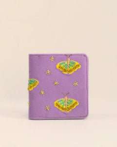 Purple wallet with butterfly designs on a beige background