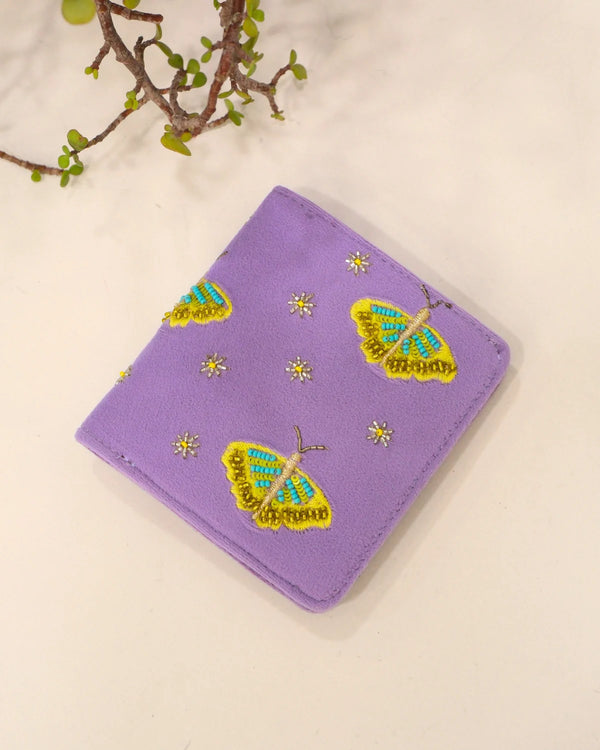 Purple wallet with butterfly designs on a beige background
