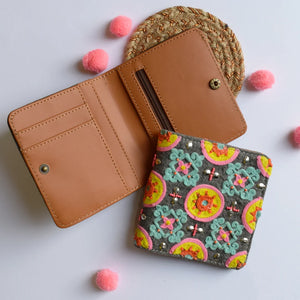 Open brown leather wallet with a colorful embroidered cardholder on a light background