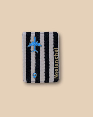 Black and white striped passport cover with embroidered blue airplane design.