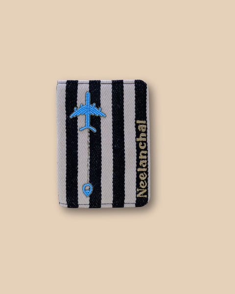 Black and white striped passport cover with embroidered blue airplane design.