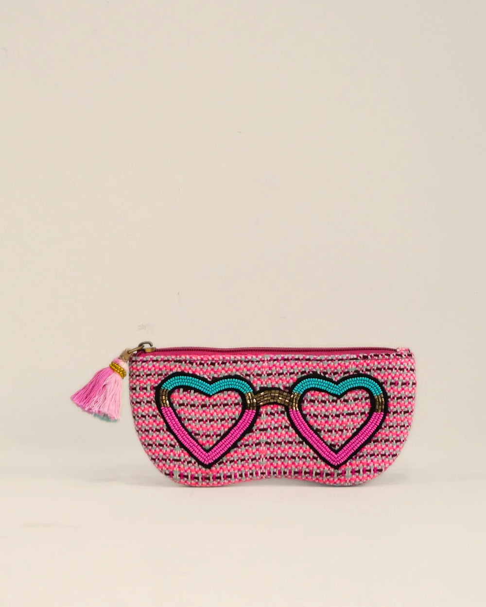 Pink pouch with heart designs and a tassel on a beige background