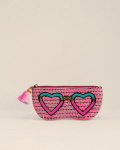 Pink pouch with heart designs and a tassel on a beige background