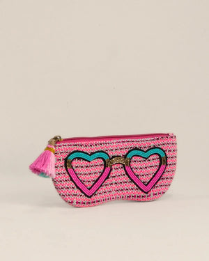 Pink pouch with heart design and tassel on a beige background