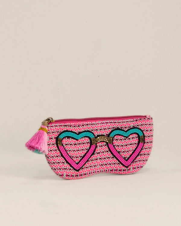 Pink pouch with heart design and tassel on a beige background