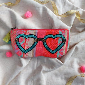 Decorative pouch with heart-shaped sunglasses design on a textured fabric background