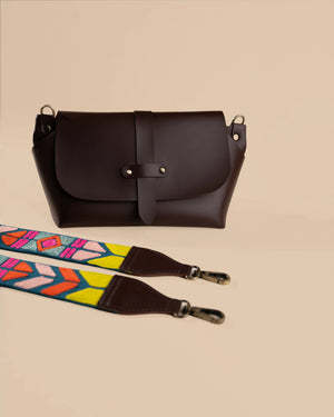Brown leather bag with a colorful strap on a beige background