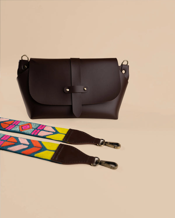 Brown leather bag with a colorful strap on a beige background
