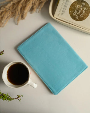 Blue notebook next to a cup of coffee on a light surface with decorative elements.