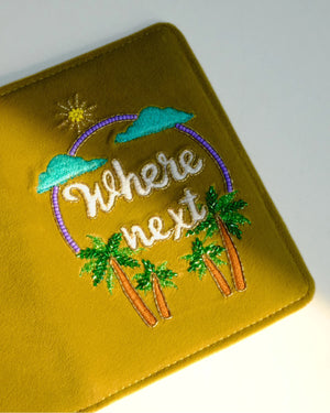 Yellow passport holder with 'Where next' text and palm tree design on a white background