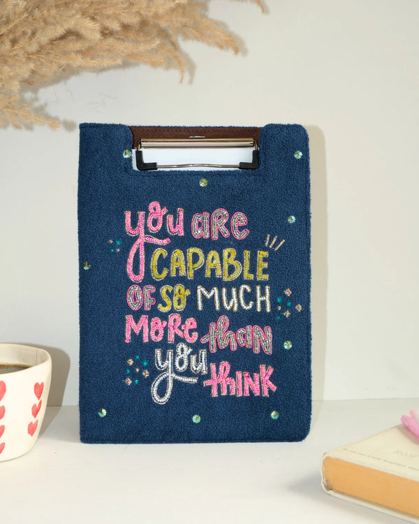 Navy blue embroidery hoop with colorful text on a white surface