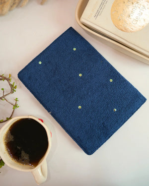 Blue towel with embroidered dots next to a cup of coffee on a light surface
