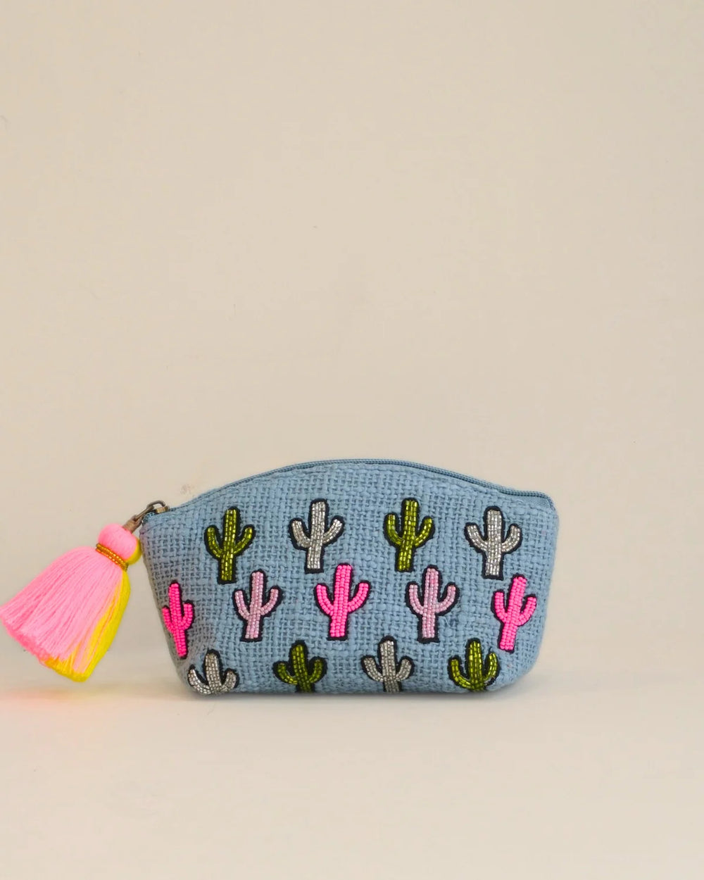 Small pouch with cactus patterns and a pink tassel on a beige background