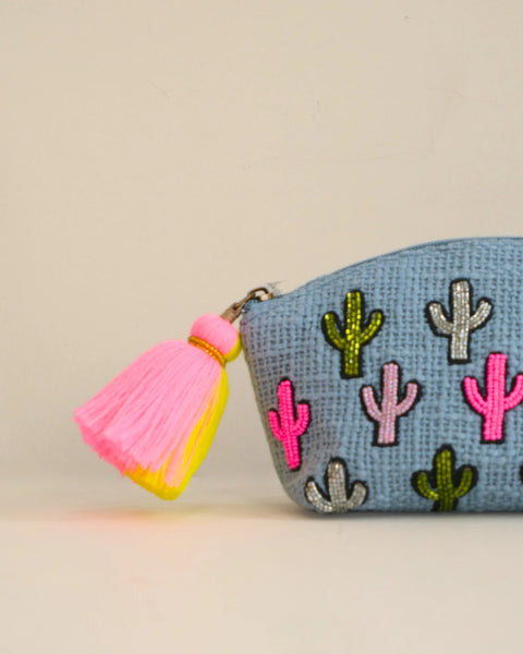 Small pouch with cactus patterns and a pink tassel on a beige background