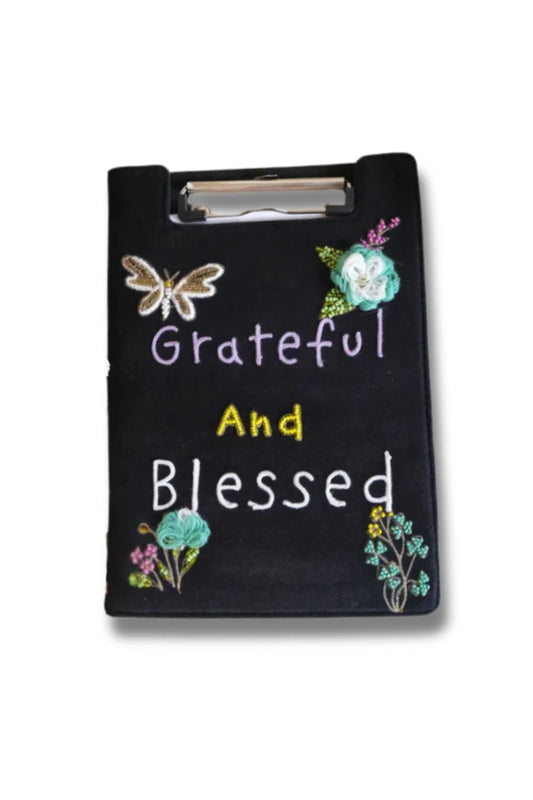 Black clipboard with floral designs and 'Grateful And Blessed' text on a black background