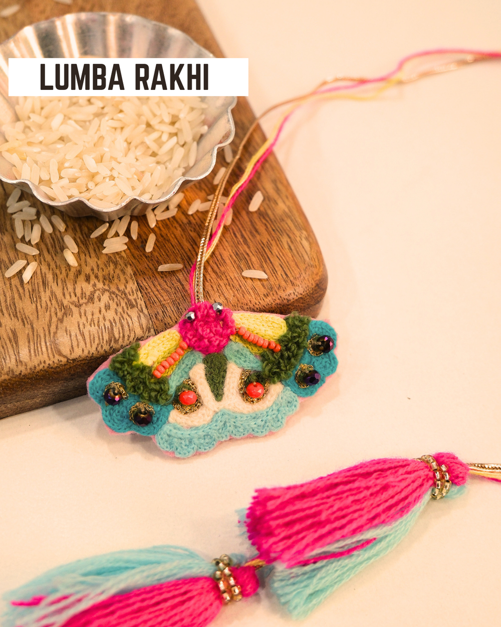Butterfly embroidered lumba rakhi placed beside a bowl of rice, styled for a festive Raksha Bandhan celebration.