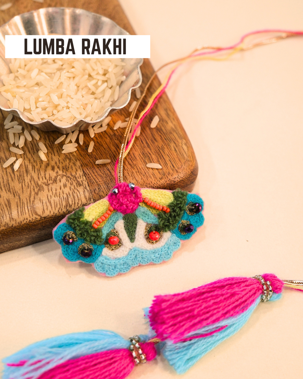 Butterfly embroidered lumba rakhi placed beside a bowl of rice, styled for a festive Raksha Bandhan celebration.
