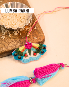Butterfly embroidered lumba rakhi placed beside a bowl of rice, styled for a festive Raksha Bandhan celebration.